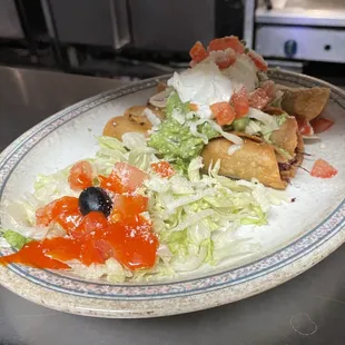 Taquitos shredded beef or chicken rolled up in corn tortillas garnished with sour cream and guacamole