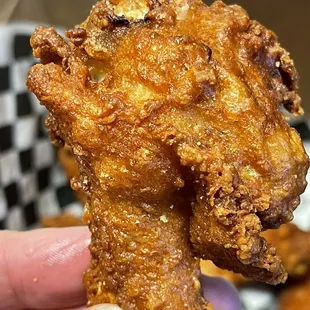 a hand holding a fried chicken