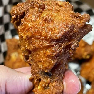 a hand holding a piece of fried chicken