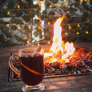 a glass of mulled on a table with a fire in the background