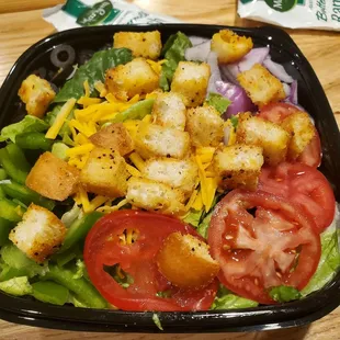 a salad with croutons and tomatoes