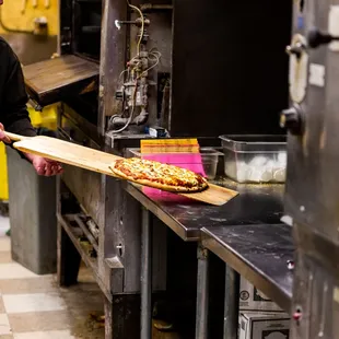  a man pulling a pizza out of the oven
