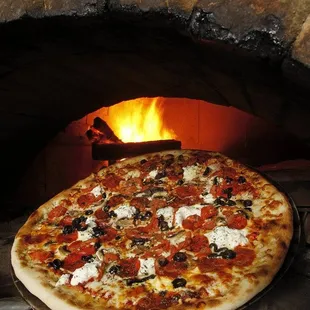 a pizza in front of a brick oven