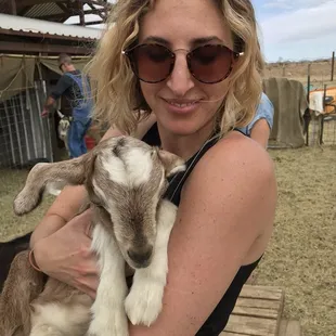 a woman holding a baby goat