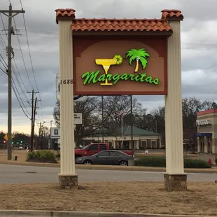 a sign for margaritas on the corner of a street