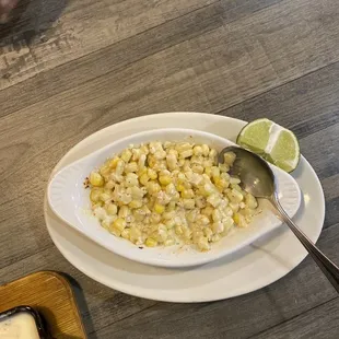 a plate of corn with a lime wedge