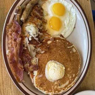 American breakfast with pancakes, 2 eggs, 2 sausages, bacons, and hash browns