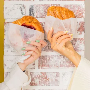 two people holding sandwiches