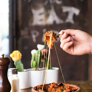 a person dipping a piece of margherita into a bowl
