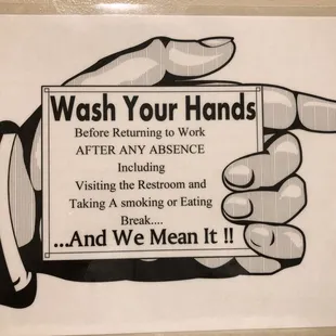 a hand holding a sign that says wash your hands before returning to work