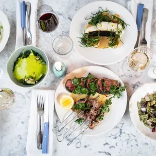 a table with plates of food and glasses of wine
