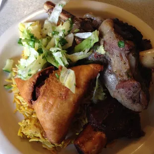 Buffet plate: lamb shank, beef ribs, samosa and salad on top of chicken briyani rice.