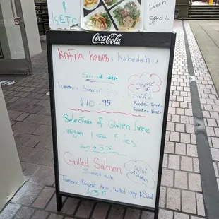 a menu board on a sidewalk