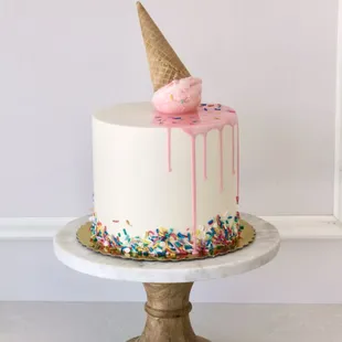 a white cake with pink icing and sprinkles