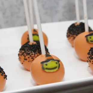 orange cake pops with black sprinkles