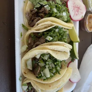 2 Lengua and 2 asada tacos with green and red salsa on the side.  asada tacos are $2.50 each and Lengua are $3.50 each.