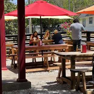 a group of people sitting at tables under umbrellas
