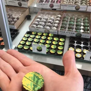 a person's hand holding a chocolate covered donut