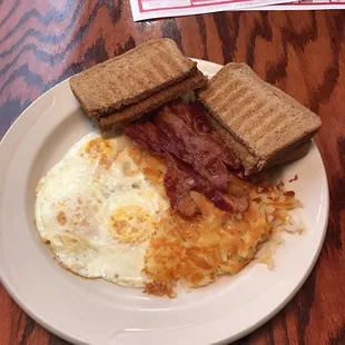 Three eggs over medium. Hash browns. Bacon. Wheat toast.