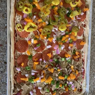 a pizza with pepperoni, peppers, and onions