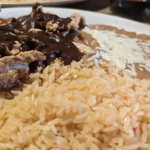a plate of rice, meat and beans