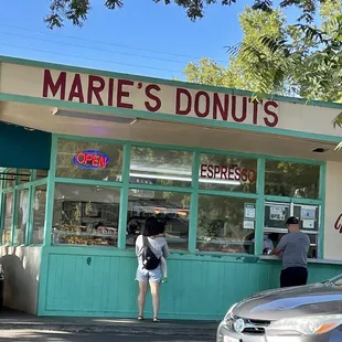 a woman standing in front of a donut shop