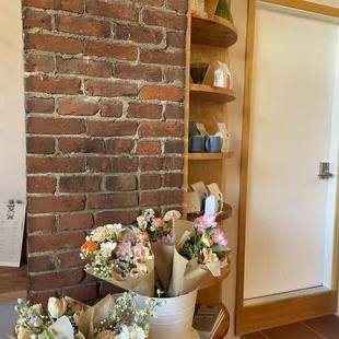 a bunch of flowers in buckets in front of a brick wall