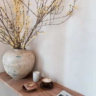 a table with a vase of flowers and a cup of coffee
