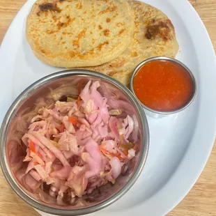 a white plate with a bowl of coleslaw and a tortilla