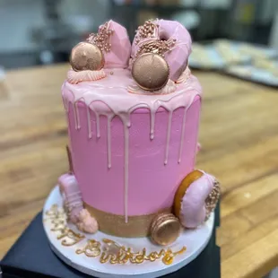 a pink cake with pink icing and pink donuts