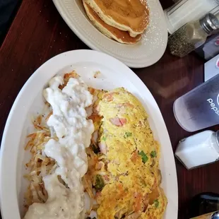 Omelet with sausage gravy on hash browns, pancakes on the side