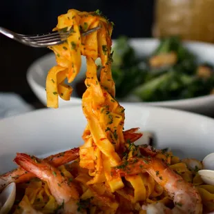 a fork lifting a piece of pasta from a bowl