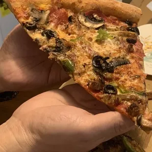 Huge slice of supreme pizza