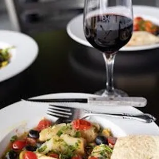 two plates of food and a glass of wine