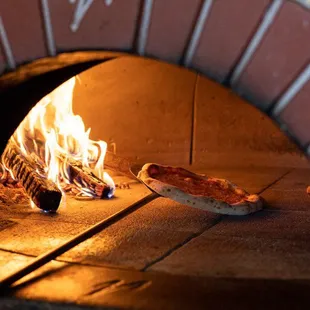 a pizza being cooked in a brick oven