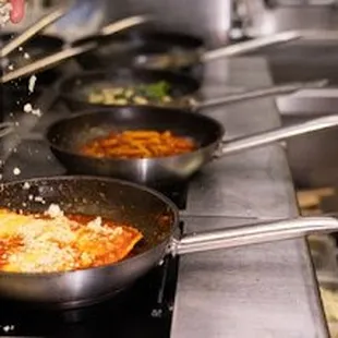 a chef sprinkling cheese over the pans