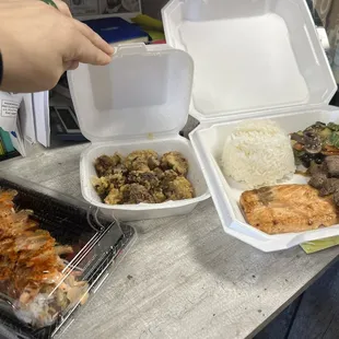 a person grabbing a piece of meat out of a styrofoam container