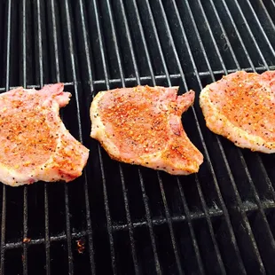three pieces of meat cooking on a grill