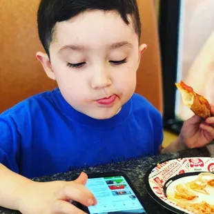 a young boy eating a piece of pizza