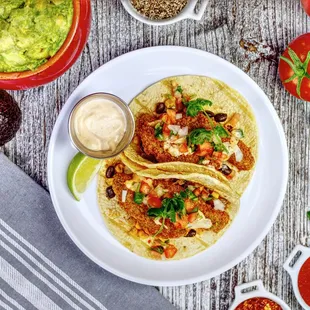 a plate of fish tacos with guacamole