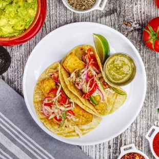 a plate of fish tacos with guacamole