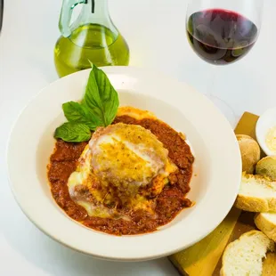 a plate of lasagna with bread and a glass of red wine