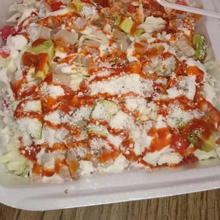a white container with sauce and vegetables
