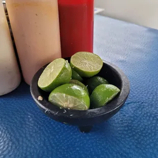 a bowl of limes and condiments