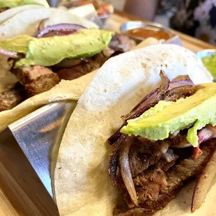 two tacos with meat, onions, and avocado