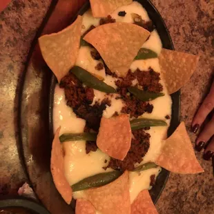 a plate of nachos with cheese and green beans