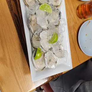 a plate of oysters with lime wedges