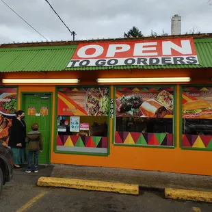 two people standing outside of a restaurant