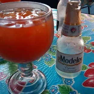 a glass of orange juice and a bottle of modelo
