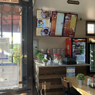 A view from the front door, looking at the cashier, overhead menu, and refrigerator